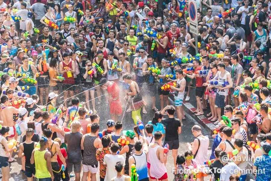 crowded street scene during the Songkran Water Festival in April on Khao San Road, Bangkok, with people using colorful water guns to celebrate the Thai New Year.